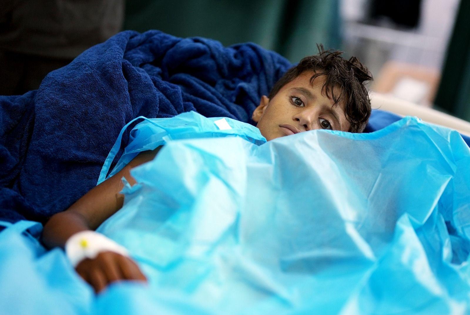 Un niño llamado Ali, que tiene heridas de metralla, yace en una cama de hospital bajo una manta azul.